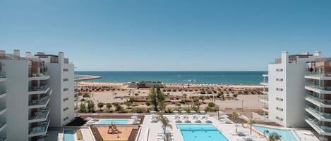Resort com piscina grande, vista para a praia e várias varandas.