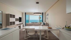 A modern kitchen with a dining area, large windows with a view of the sea, and a ceiling light fixture. - Dom Pedro Residences  (Loulé)