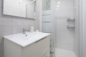 Features a sleek vanity, sink, and glass shower enclosure.