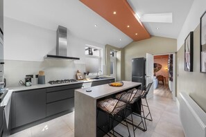 Une cuisine moderne dotée d’un îlot central, d’une cuisinière intégrée et d’une grande fenêtre.