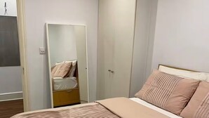 Un dormitorio con cama, armario y espejo.