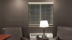A room with two leather armchairs, a small table with a lamp, a heater, and a window with blinds. - Cozy 1-bedroom hotel in delightful Huntersville up to 2 people (Huntersville)