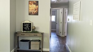 Un pasillo con una consola que exhibe un cartel y un globo terráqueo, y una puerta que da a otra habitación.