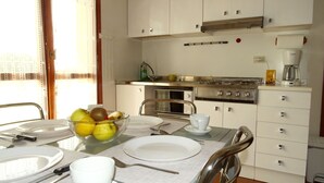Une cuisine avec des meubles blancs, une cuisinière, un four et une machine à café.