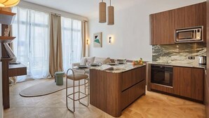 A modern kitchen with wooden cabinets, a built-in microwave, and a marble countertop. - Superb Apartment on the Champs Elysees (Paris)