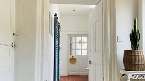 Un couloir aux murs blancs, avec un sol carrelé, et un chat assis par terre.