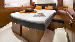 A modern, well-lit bedroom with a large bed, bedside tables, and a built-in heater. - Luxurious 55-Foot Yacht with Captain & First Mate (Sarasota)