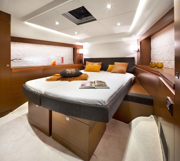 A modern, well-lit bedroom with a large bed, bedside tables, and a built-in heater.