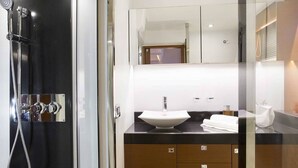 A modern bathroom with a glass-enclosed shower, a white sink, and wooden cabinets. - Luxurious 55-Foot Yacht with Captain & First Mate (Sarasota)
