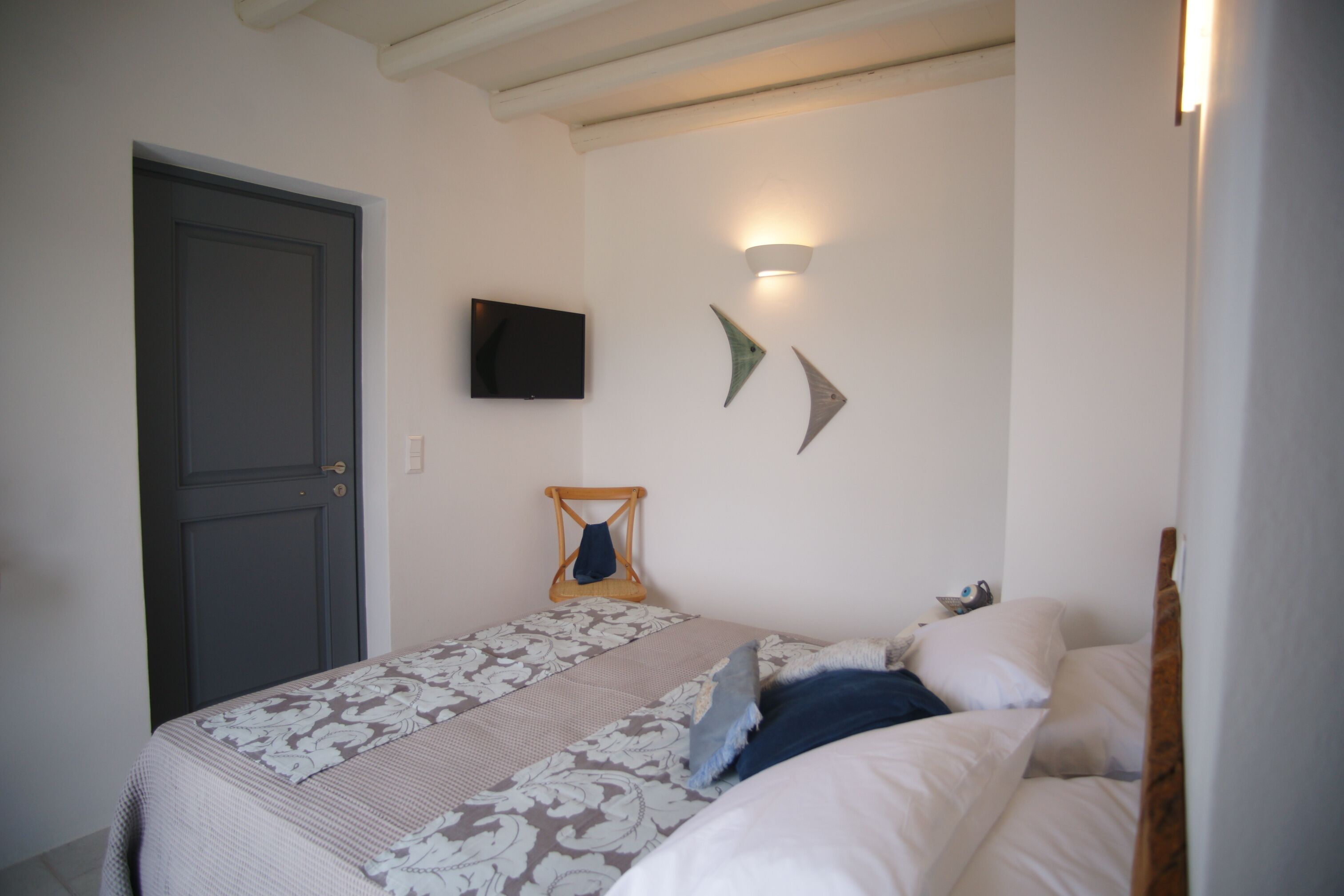 A bedroom with a bed, a television, and wall-mounted light fixtures.