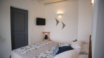 A bedroom with a bed, a television, and wall-mounted light fixtures.