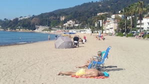 A beach with people sunbathing, umbrellas, and beach chairs.