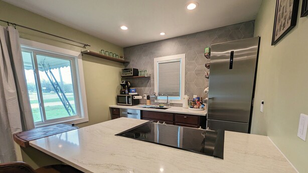 A modern kitchen with a large island, stainless steel appliances, and a view of the outdoors. - Sleek and Central Small Home ~ Close to everything (Flint)