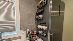A kitchen with a stainless steel refrigerator, a coffee maker, and various snacks on the counter. - Sleek and Central Small Home ~ Close to everything (Flint)