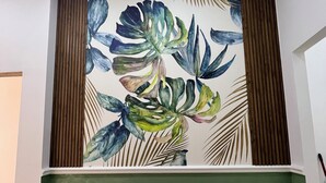 Una habitación con pared verde, un mural decorativo de hojas y dos paneles blancos.