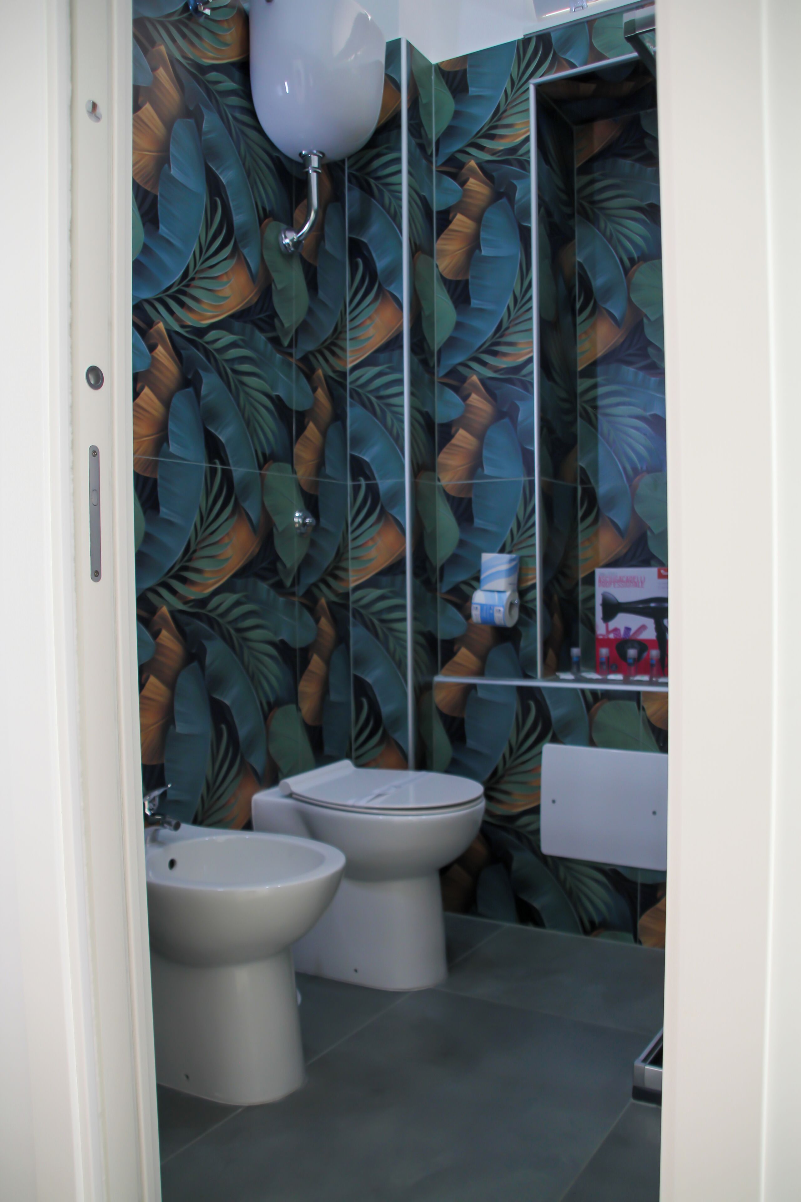 Een badkamer met toilet, bidet en spiegel.