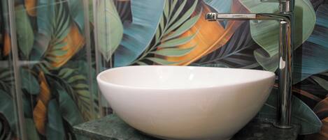 A white vessel sink mounted on a dark countertop with a chrome faucet.
