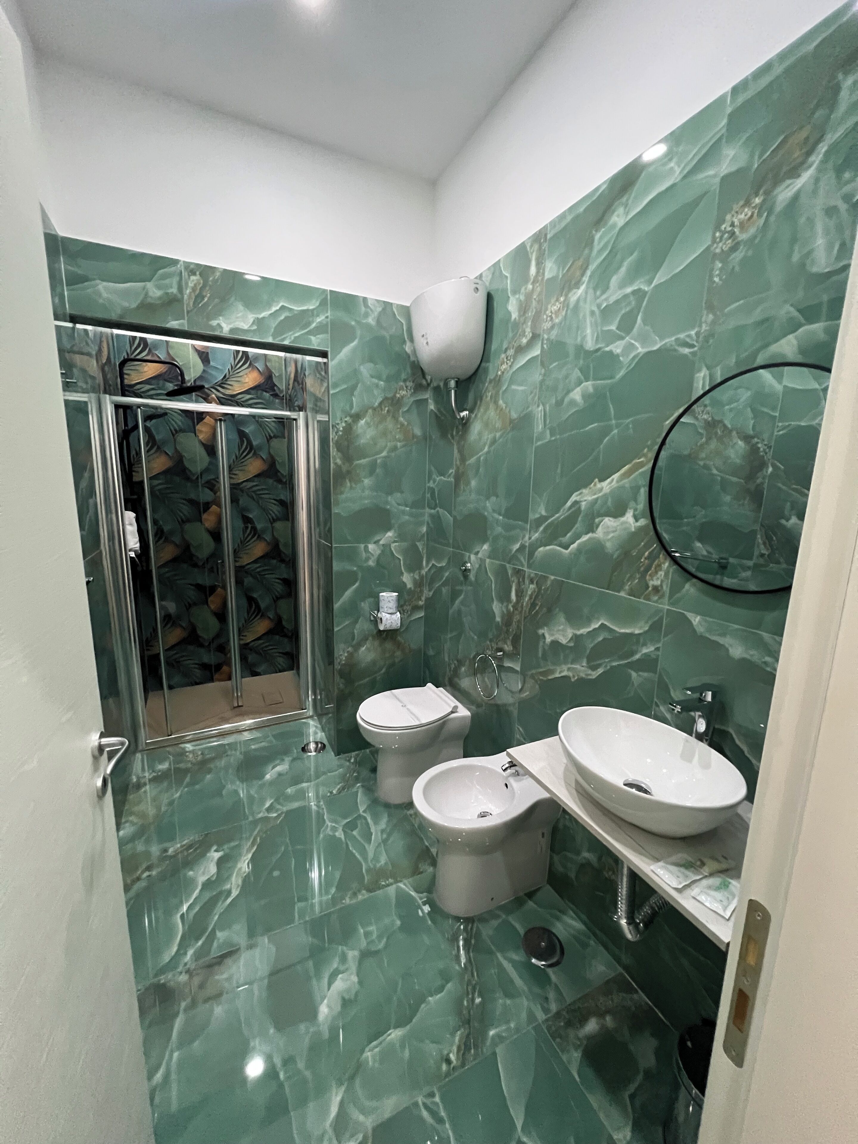 A bathroom with a shower, two toilets, and a sink.