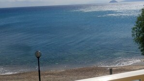 Une vue sur la mer, avec un ciel dégagé, une plage de sable et une île lointaine.