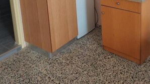 Une cuisine de taille réduite, équipée d’un évier, d’un petit réfrigérateur et d’un meuble en bois.