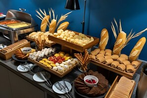 A buffet with various breads, pastries, and desserts.