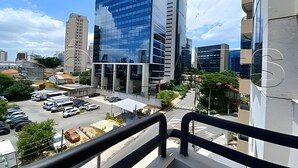 A view of a parking lot with several cars, a modern building with reflective glass windows, and a clear sky.