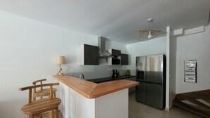 Una cocina moderna con una isla central, taburetes de bar, una estufa y un refrigerador.