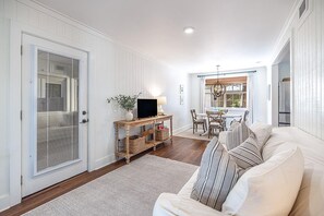 A living room with a sofa, TV, and a dining area with chairs and a table.