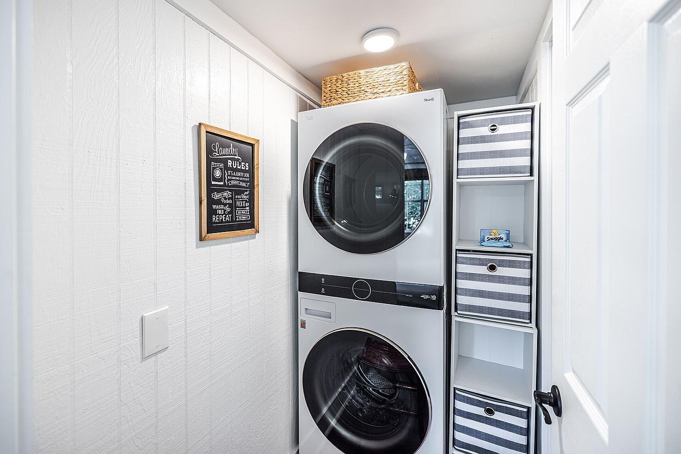 A laundry room with two stacked washing machines and a drying rack.