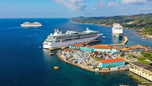Un vaixell de creuer amarrat en un port amb un port esportiu i edificis de colors a prop.