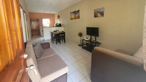 Un saló amb un sofà, una televisió i una zona de menjador amb cadires i una taula.