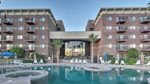 Un hotel con zona de piscina, varios balcones y una entrada principal.