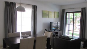 Un espace repas comprenant une table et des chaises, un téléviseur et un canapé.