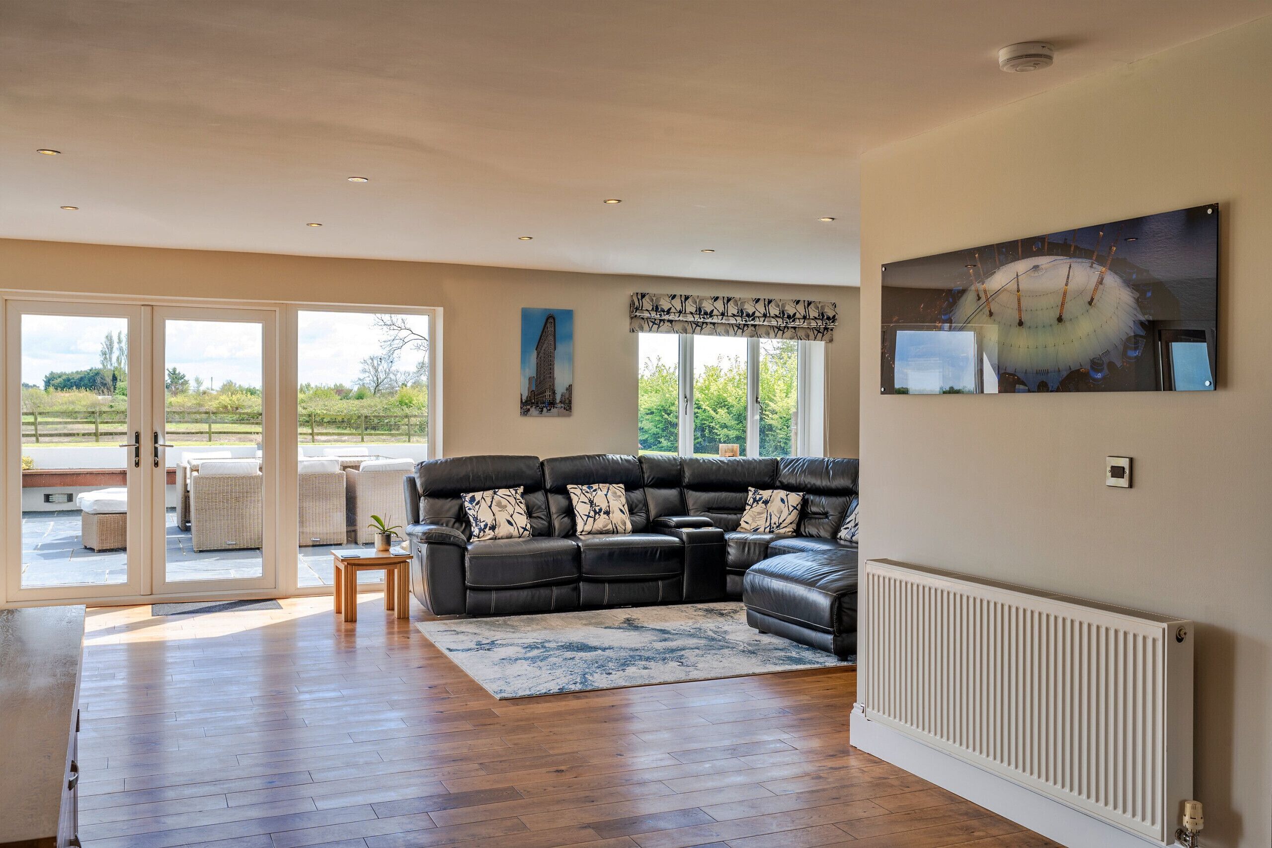 A spacious living room with a sectional sofa, a large window, and a radiator.