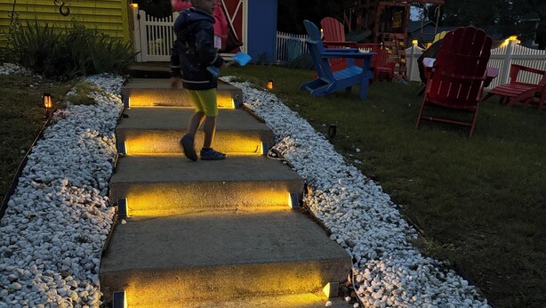Un niño subiendo por una escalera de piedra con escalones iluminados.
