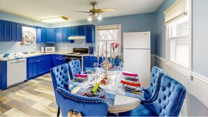 Una cocina moderna con armarios azules, una mesa de comedor para seis personas y un ventilador de techo.