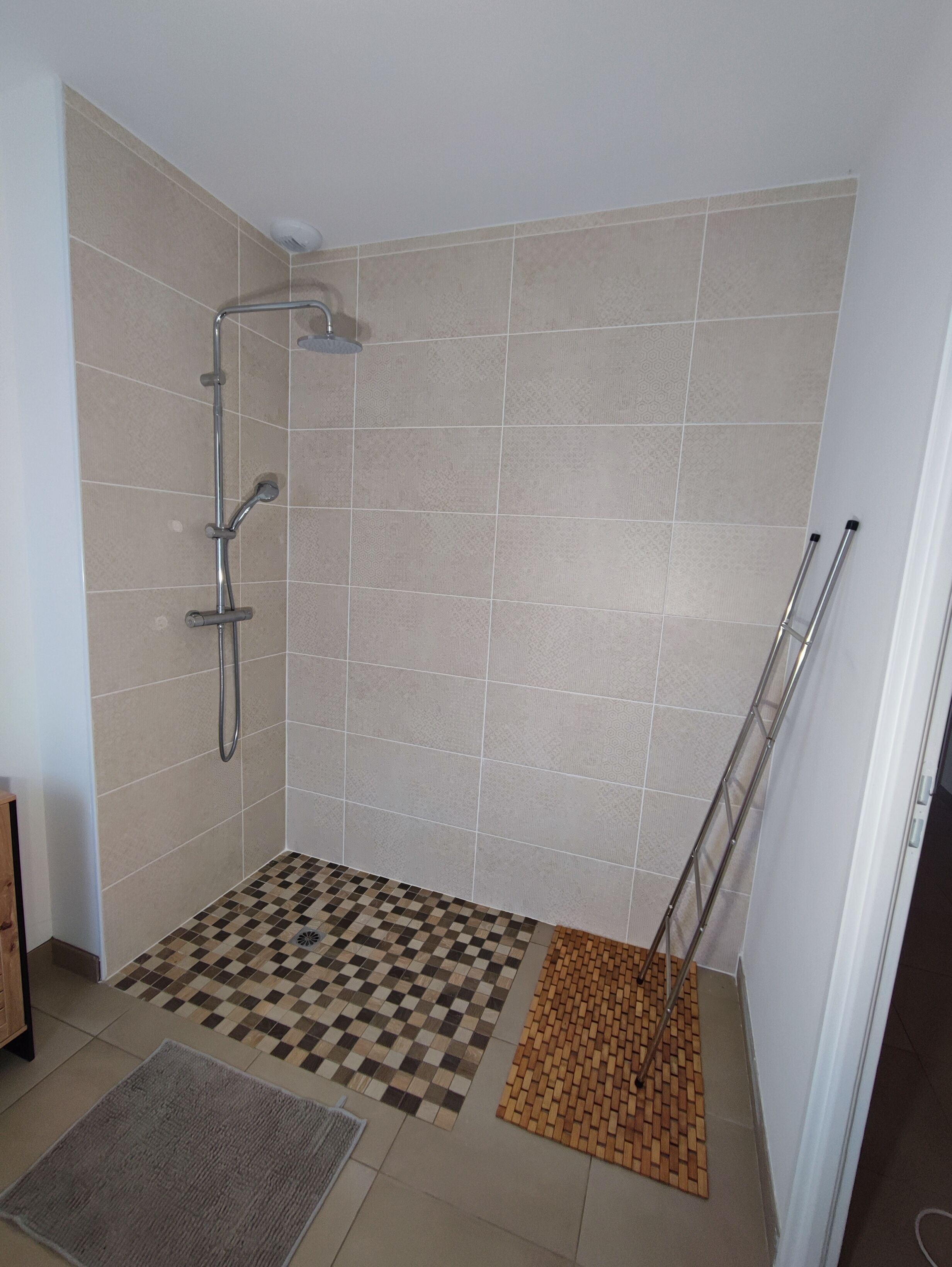 Un bagno con pavimento a scacchi, doccia a pavimento e soffione.