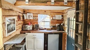 Een kleine keuken met houten wanden, een eettafeltje en een koelkast.