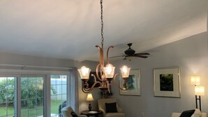 Amplia sala de estar con candelabro, ventilador de techo y comedor con mesa dispuesta para dos.