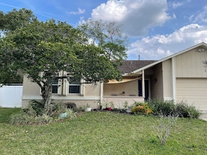 A single-story house with a covered porch, a tree in front, and a clear sky. - Peaceful family retreat-centrally located for attraction options! (Longwood)