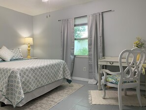 A bedroom with a bed, a desk, a chair, a lamp, and a window with curtains. - Peaceful family retreat-centrally located for attraction options! (Longwood)