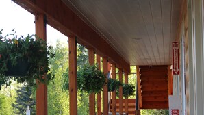 A covered wooden deck with railings and hanging plants, leading to a building entrance. - Eagle River Lodge (Eagle River)