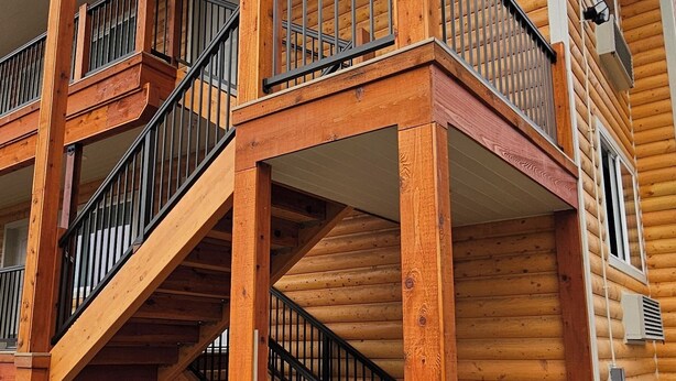 A multi-story wooden building with a balcony on the second floor and a staircase leading to the third floor. - Eagle River Lodge (Eagle River)