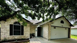 A two-story house with a stone facade, a garage, and a covered entryway. - 3 bedroom 2 bathroom home in heart of Buda, TX. (Buda)