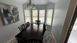 A dining room with a dark wooden table and chairs, a chandelier, and a painting on the wall. - 3 bedroom 2 bathroom home in heart of Buda, TX. (Buda)