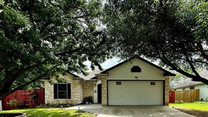 A two-story house with a garage, a stone facade, and a large tree in front. - 3 bedroom 2 bathroom home in heart of Buda, TX. (Buda)