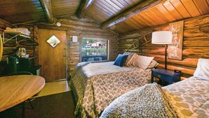 A cozy cabin-style room with a bed, a desk, and a dining table.