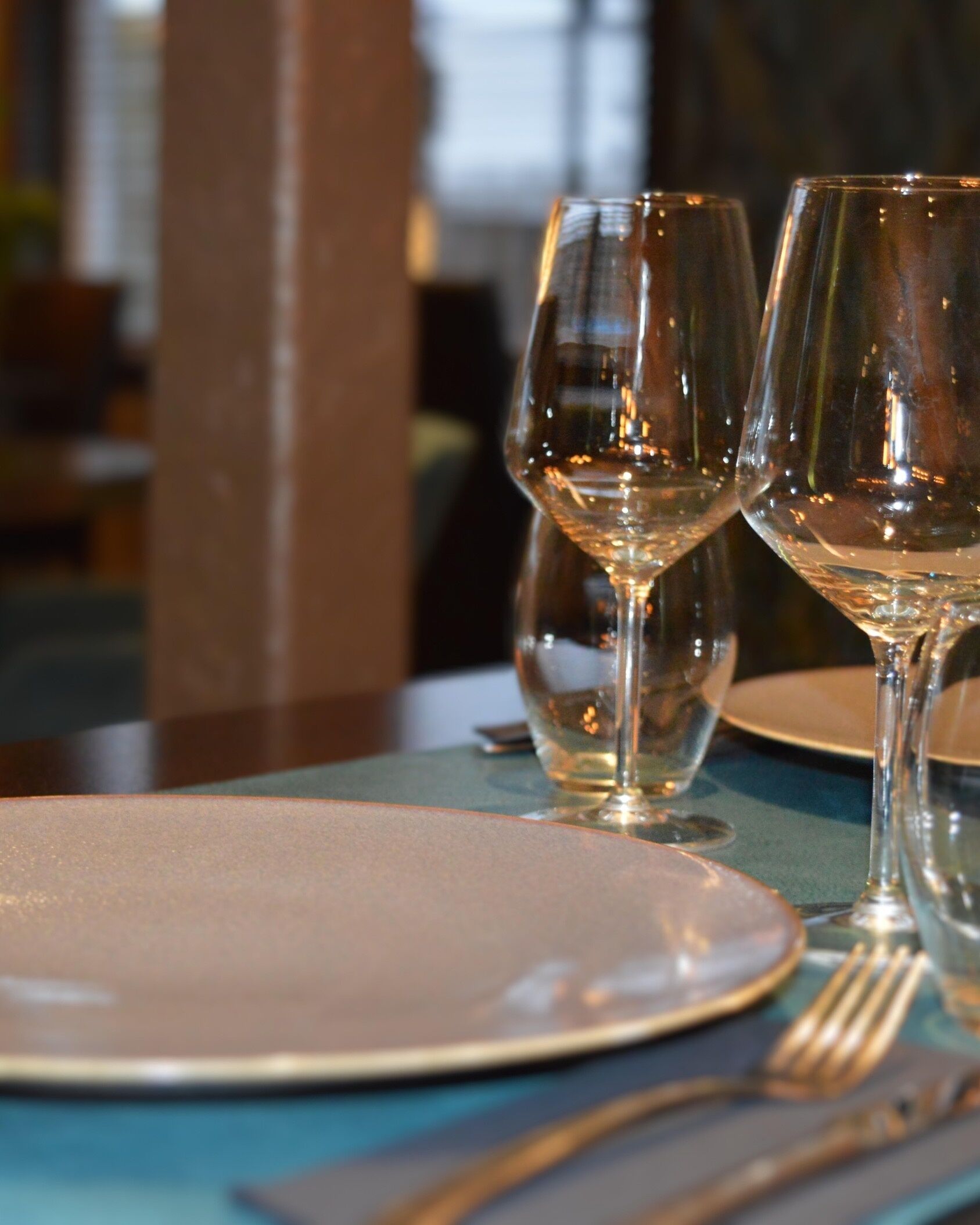 A table set with wine glasses, plates, and cutlery.