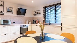Eine moderne Küche mit weißen Schränken, einer Mikrowelle, einer Kaffeemaschine und einer Vase mit Blumen auf der Arbeitsfläche.