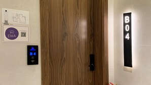 Une porte en bois dotée d’une serrure numérique, d’un extincteur et d’une pancarte indiquant le numéro de la pièce : B04.
